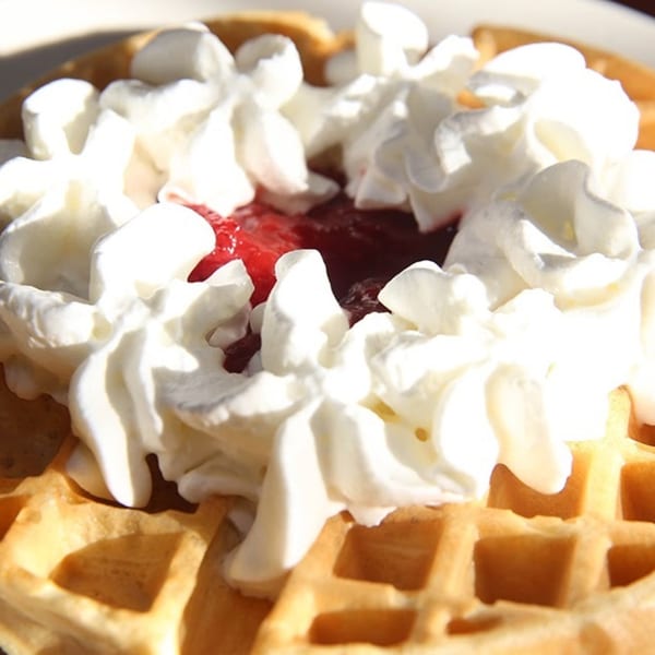 Golden waffle topped with whipped cream and a dollop of red jam, a Dempsey's breakfast item.