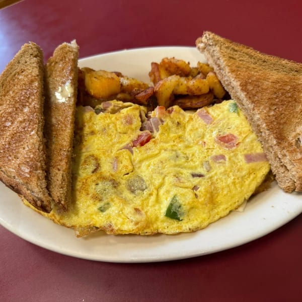 A Dempsey's breakfast plate with a ham and pepper omelet, home fries, and buttered toast.