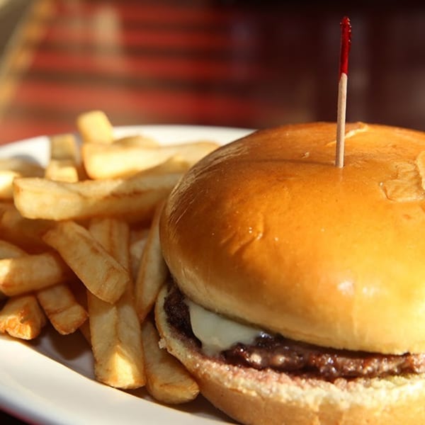 A Dempsey's cheeseburger with a red toothpick and a side of golden french fries.